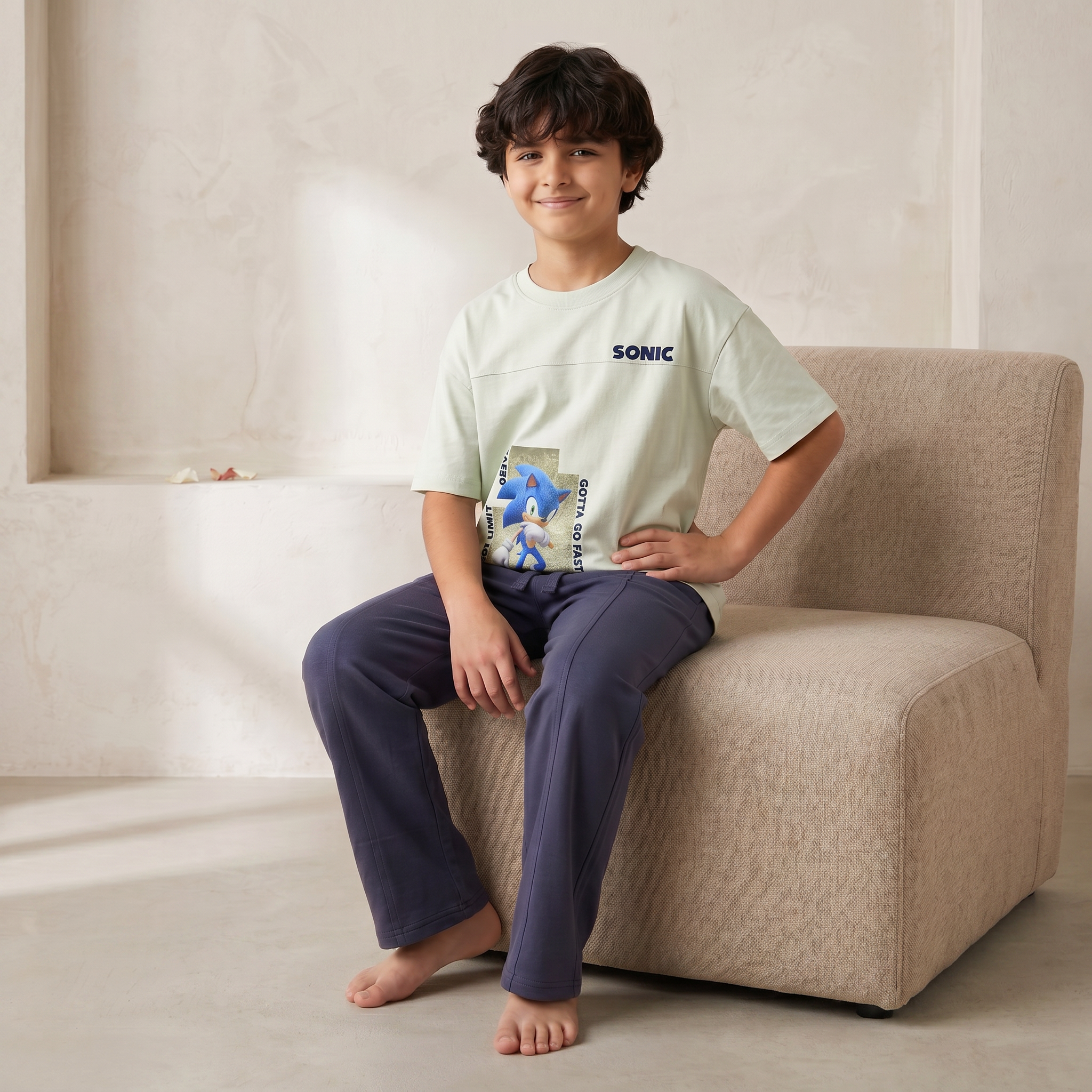 Child wearing a Sonic the Hedgehog t-shirt sitting on a beige chair.